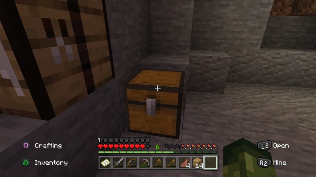 The player looking at a yellow chest on the stone floor next to a crafting table.