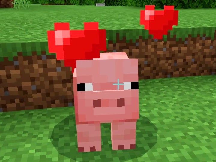 Pink pig wit red hearts over their head standing in a grassy area.