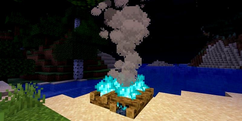 A campfire with blue-green fire on a beach at night.