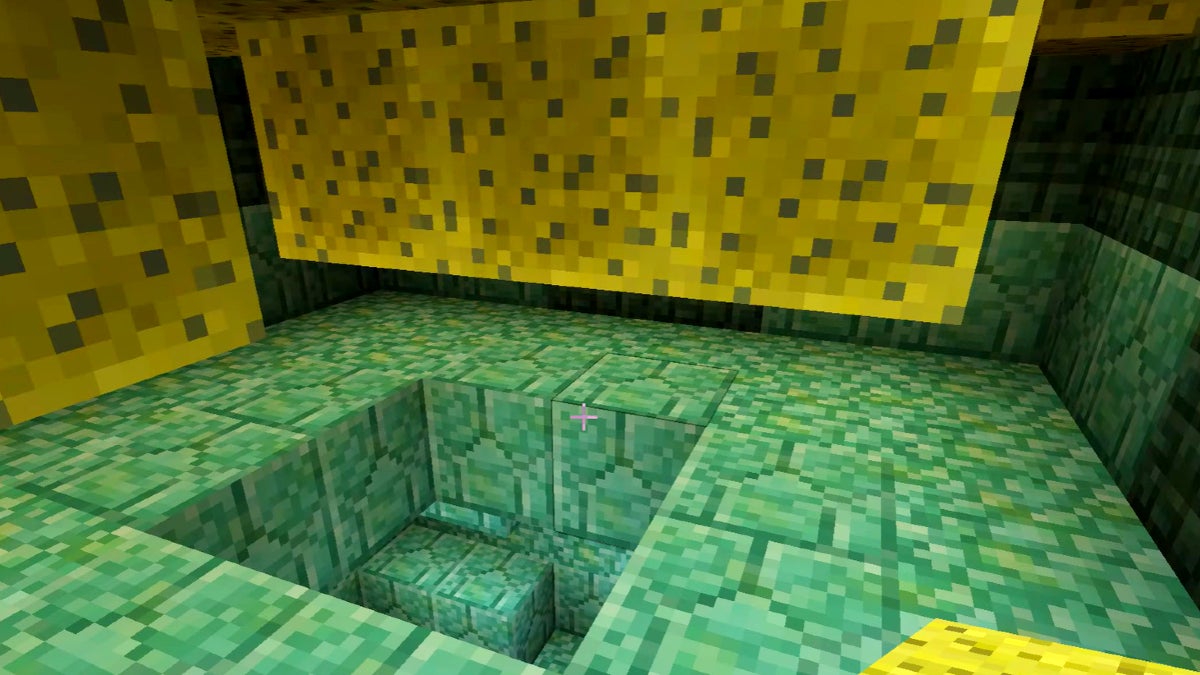 The player in a dry sponge room within an ocean monument. There are sponges on the ceiling and the surroundings are made of green blocks.