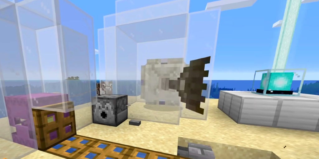 An elder guardian and shulker trapped in glass structures on a sandy island. There is also a beacon and a dispenser nearby.
