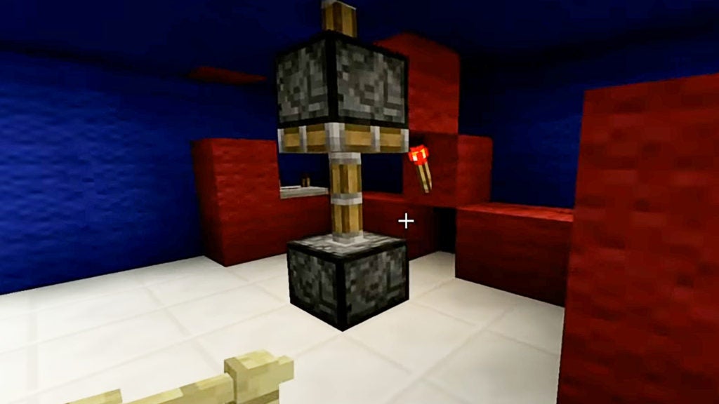 There are 2 pistons on top of one another and a redstone torch nearby powering them. This contraption is hidden behind a wall.