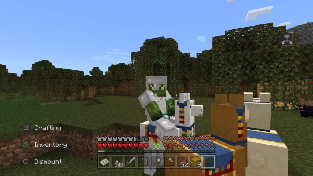 A player in iron armor riding a white trader llama that has a red, yellow, and blue carpet.