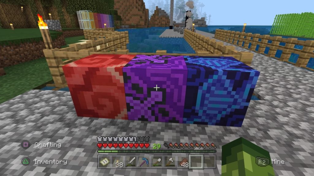 Red, purple, and blue blocks lined up on some gray cobblestone.