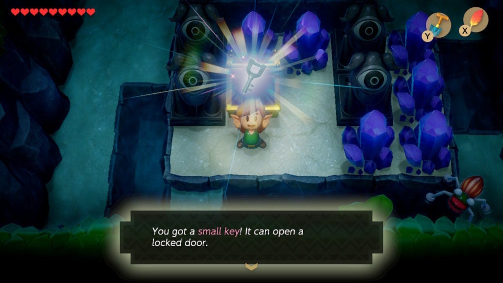 Link holding a small key above his head while surrounded by purple crystals.