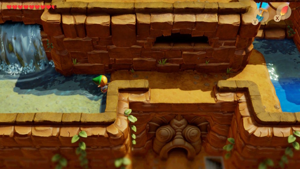 Link standing near a ledge above the entrance to the 4th dungeon in the game that looks like a fish's face.