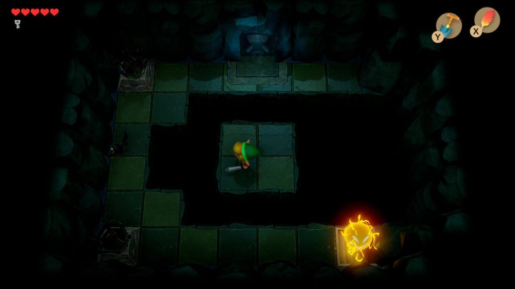 A dark room with an island in the middle surrounded by floor gaps.