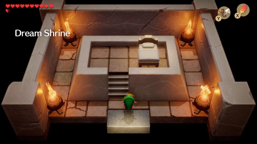 Link looking at a bed on a raised platform within a chamber lit by 2 torches.