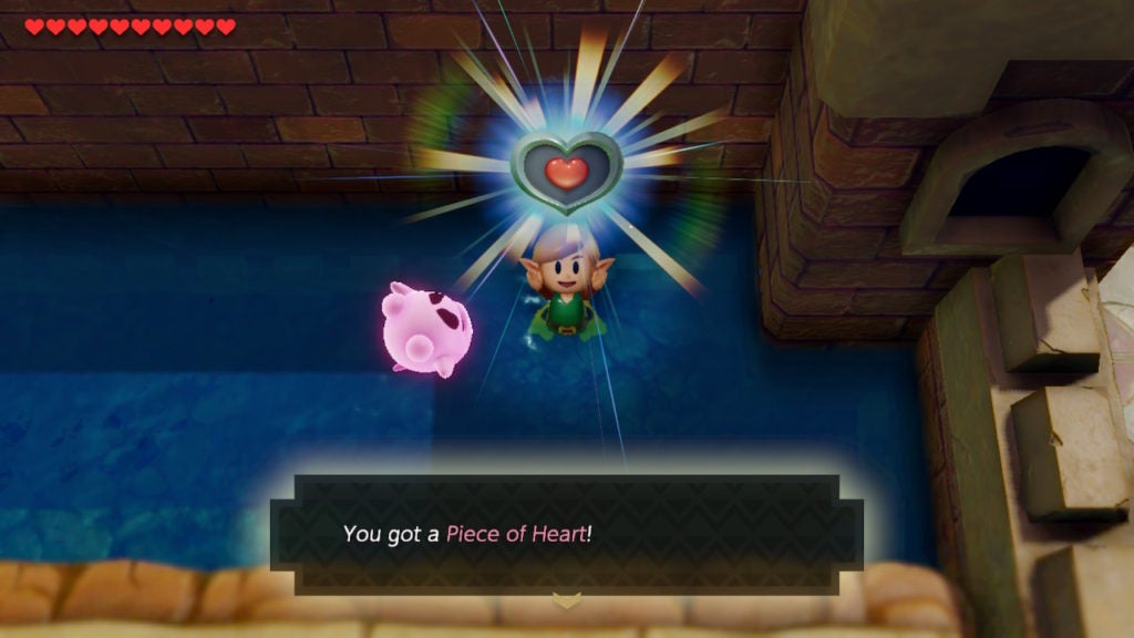 Link holding up a Heart Piece while swimming and with the pink ghost nearby.