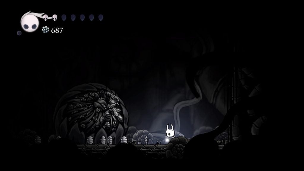 The Knight standing next to the largest Geo deposit in Hollow Knight.