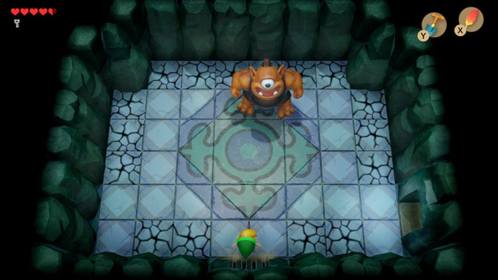Link facing off against a large orange cyclops in a room with cracked floor tiles around its edges.
