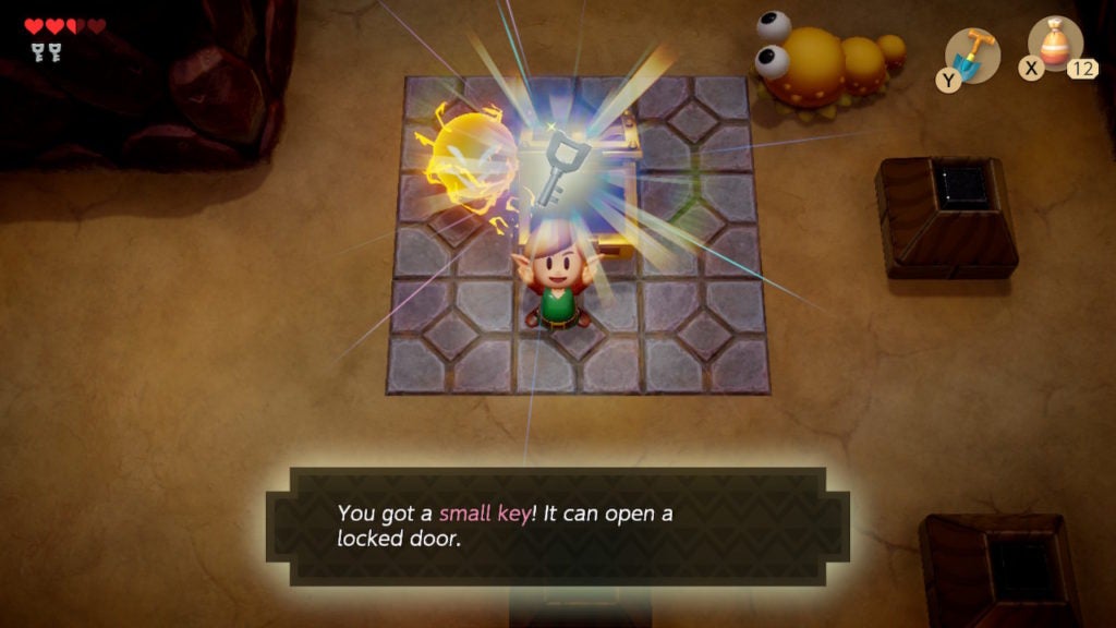 Link holding up a key that they just found in a chest in a big room in Level 1 - Tail Cave.