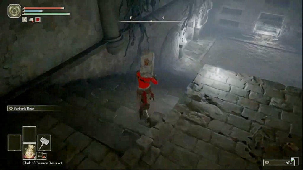 A player with a hammer walking down some stairs in a catacomb's dimly lit room.