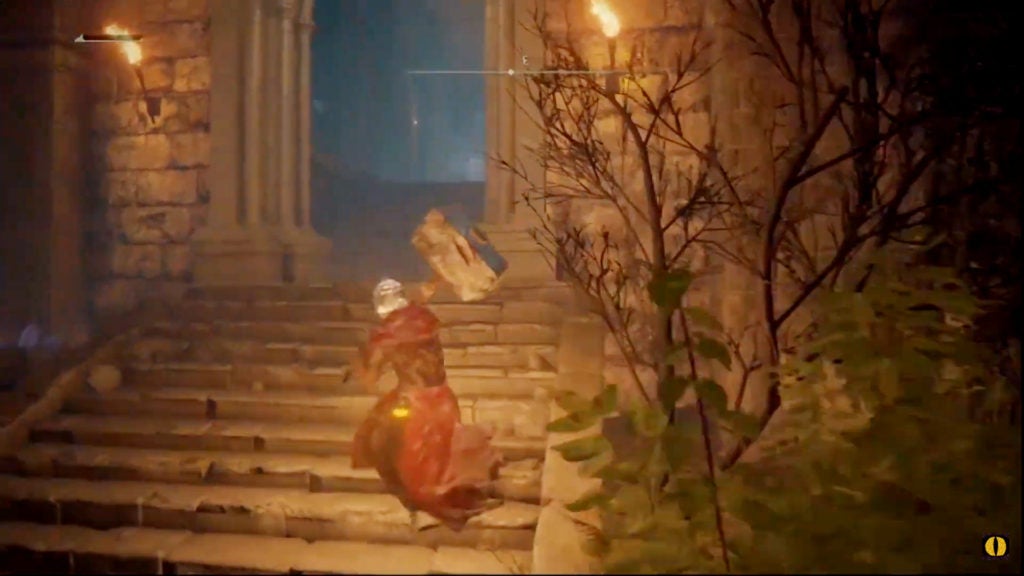 The player walking up the stairs to an open doorway flanked by lit torches.