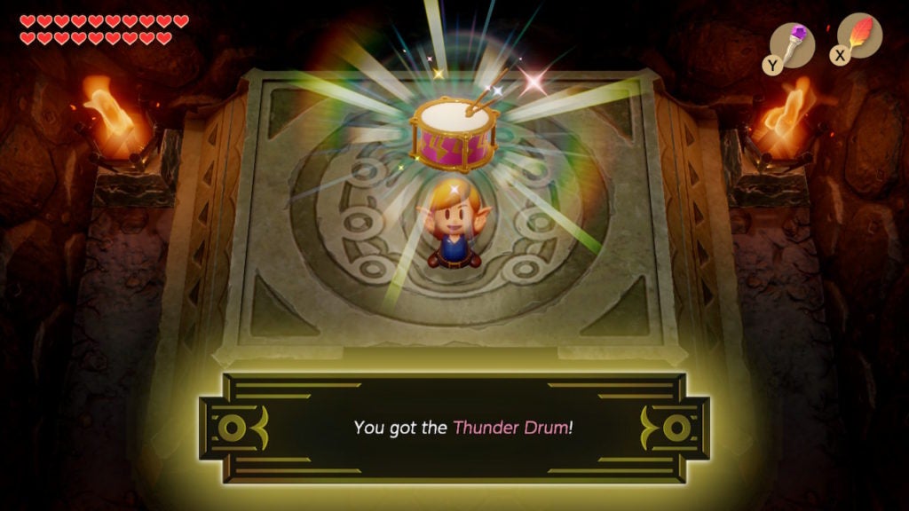 Link holding up a red and gold snare drum that has two drumsticks.