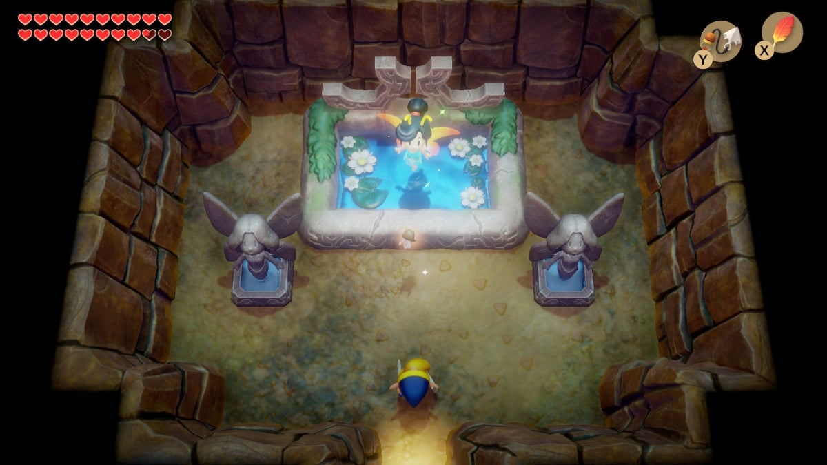 Link looking at a Great Fairy in a cave. The Great Fairy is a humanoid with yellow wings who is hovering above a blue pond.