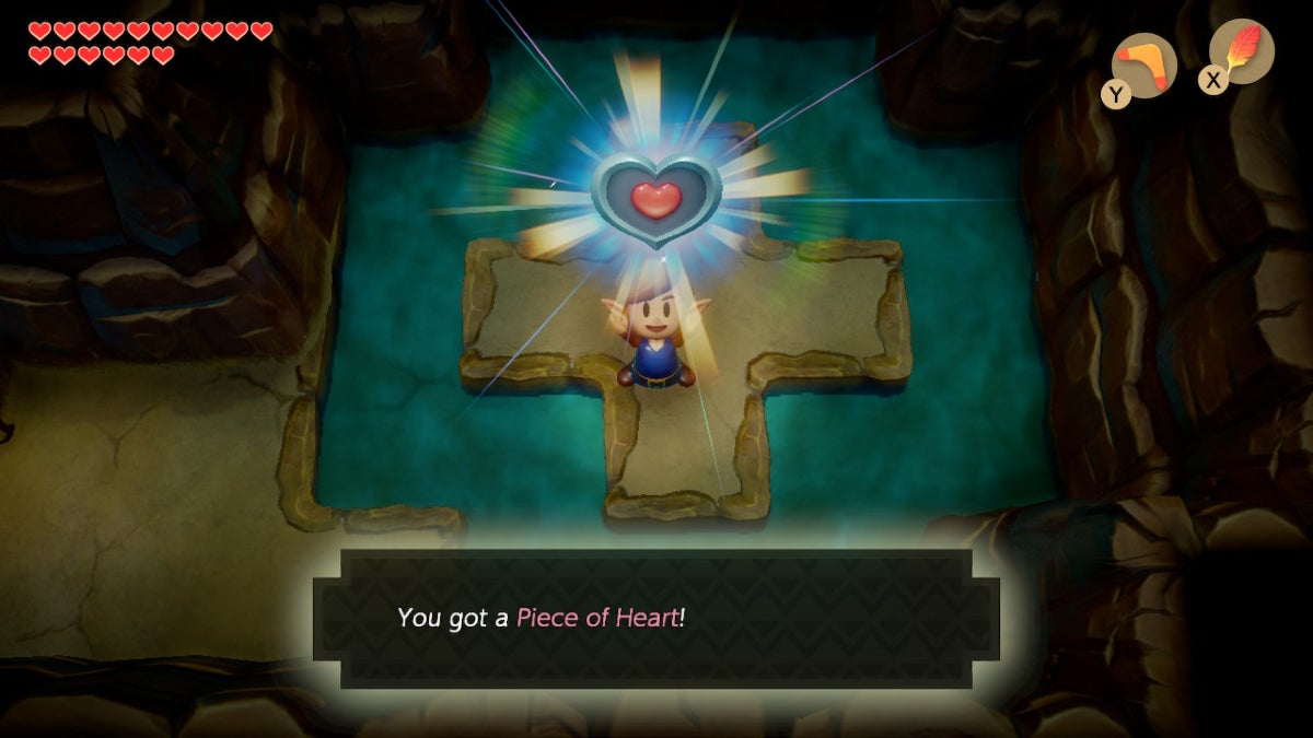 Link holding up a Heart Piece in a cave with shallow water.