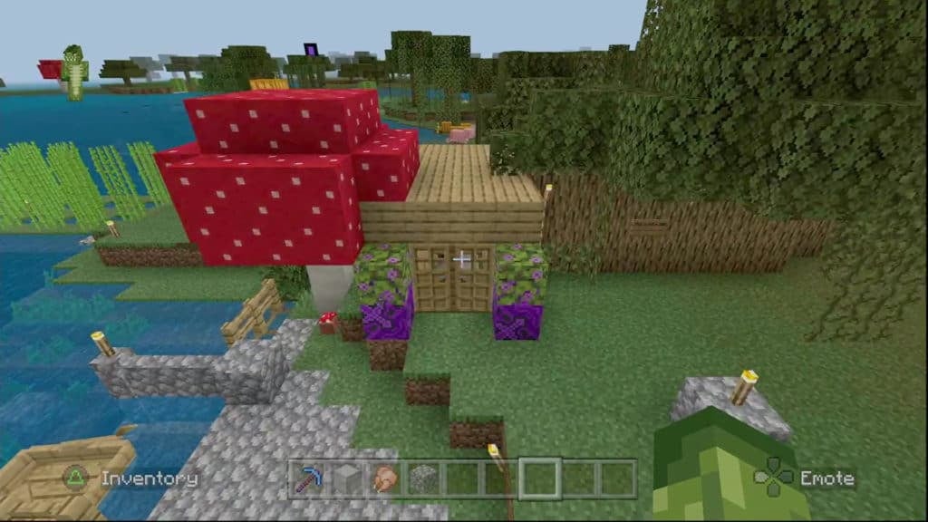 An aerial view of a small house made from wood planks. It is flanked by a giant red mushroom and a line of oak trees.