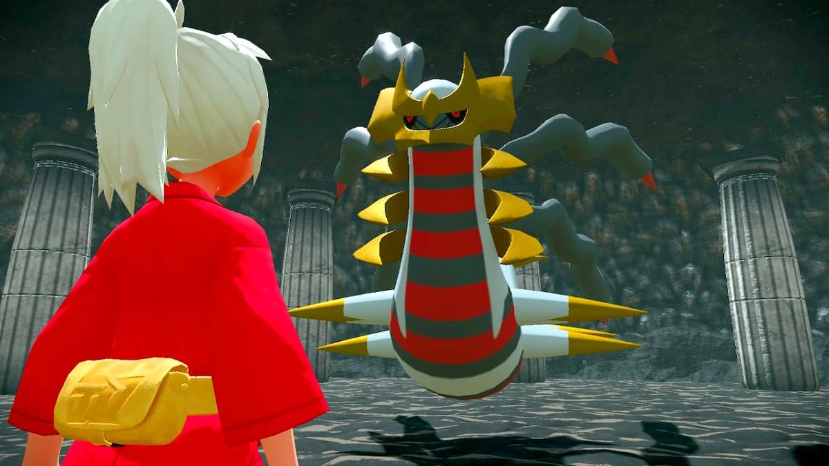 A player in red clothes facing off against Giratina in a dark cave.