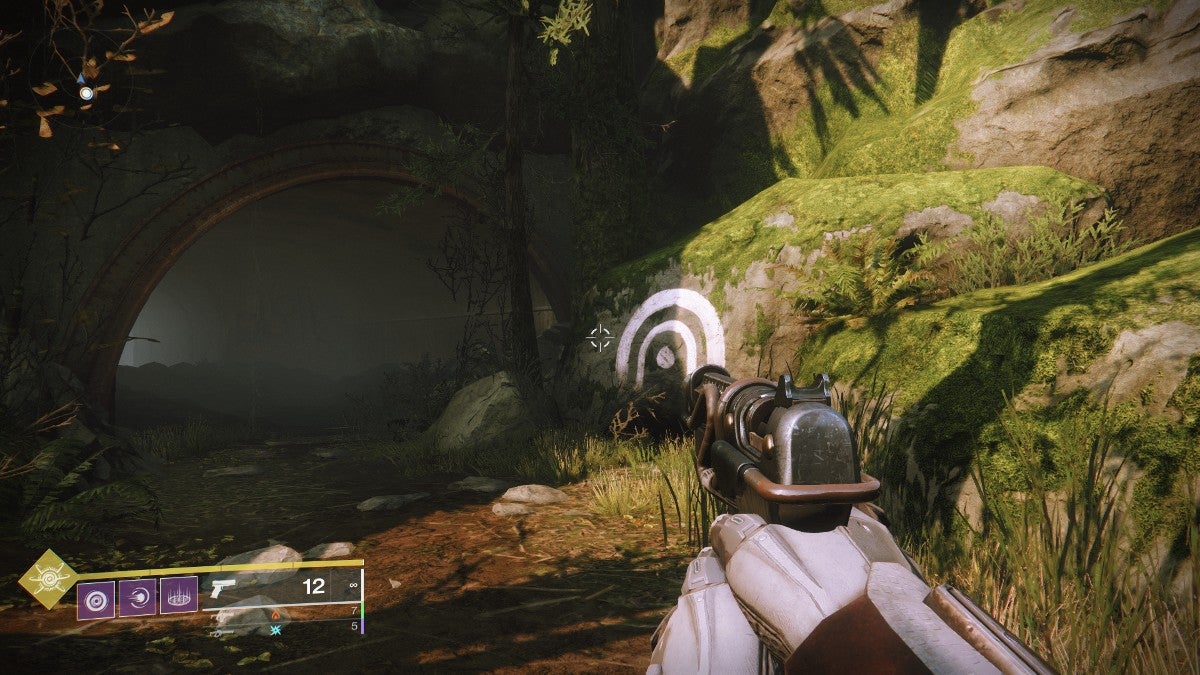 A white symbol that looks like two arches over a dot is painted on a rock just outside of a cave.