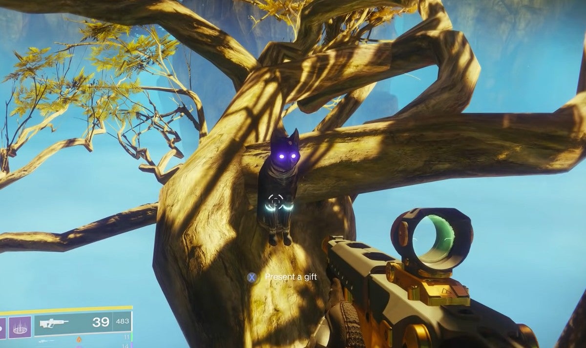 The fifth cat statue in the Dreaming City sitting on a horizontal tree trunk near a cliff.