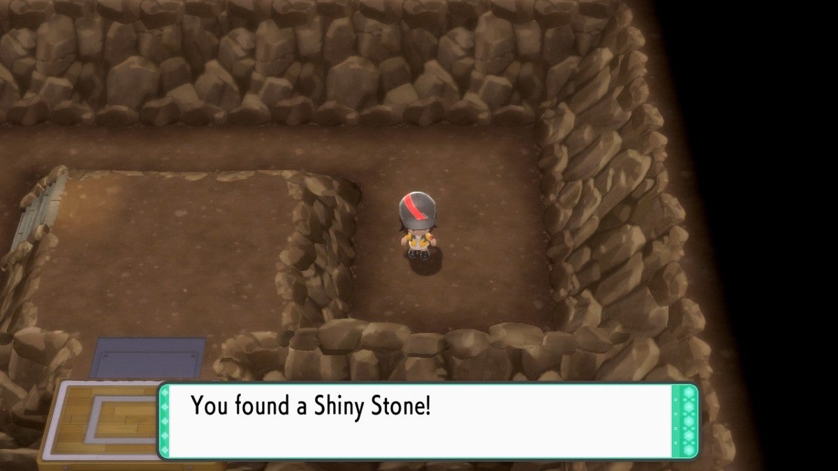 A player in yellow and black clothes finding a Shiny Stone in the cave on Iron Island.