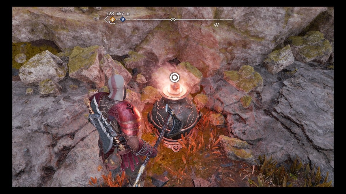 Kratos looking at a glowing red pot with a button prompt on it.