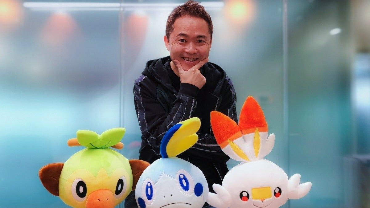 Junichi Masuda posing with some Pokémon stuffed animals.