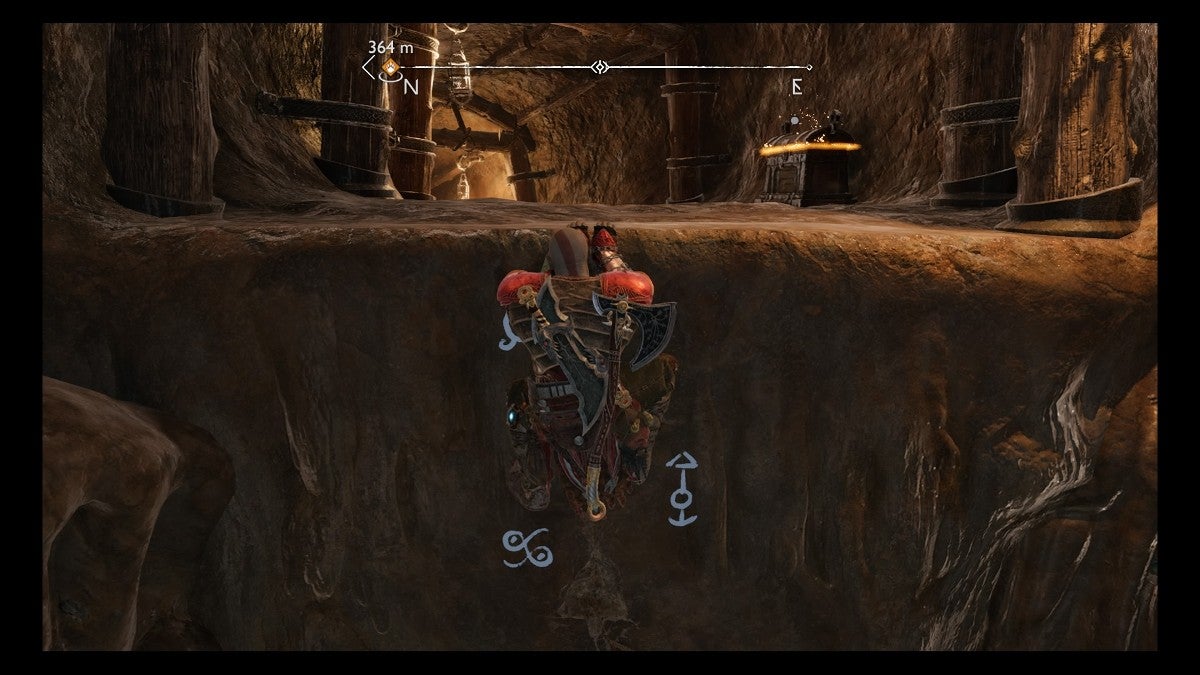 Kratos climbing a ledge with a small chest at the top.