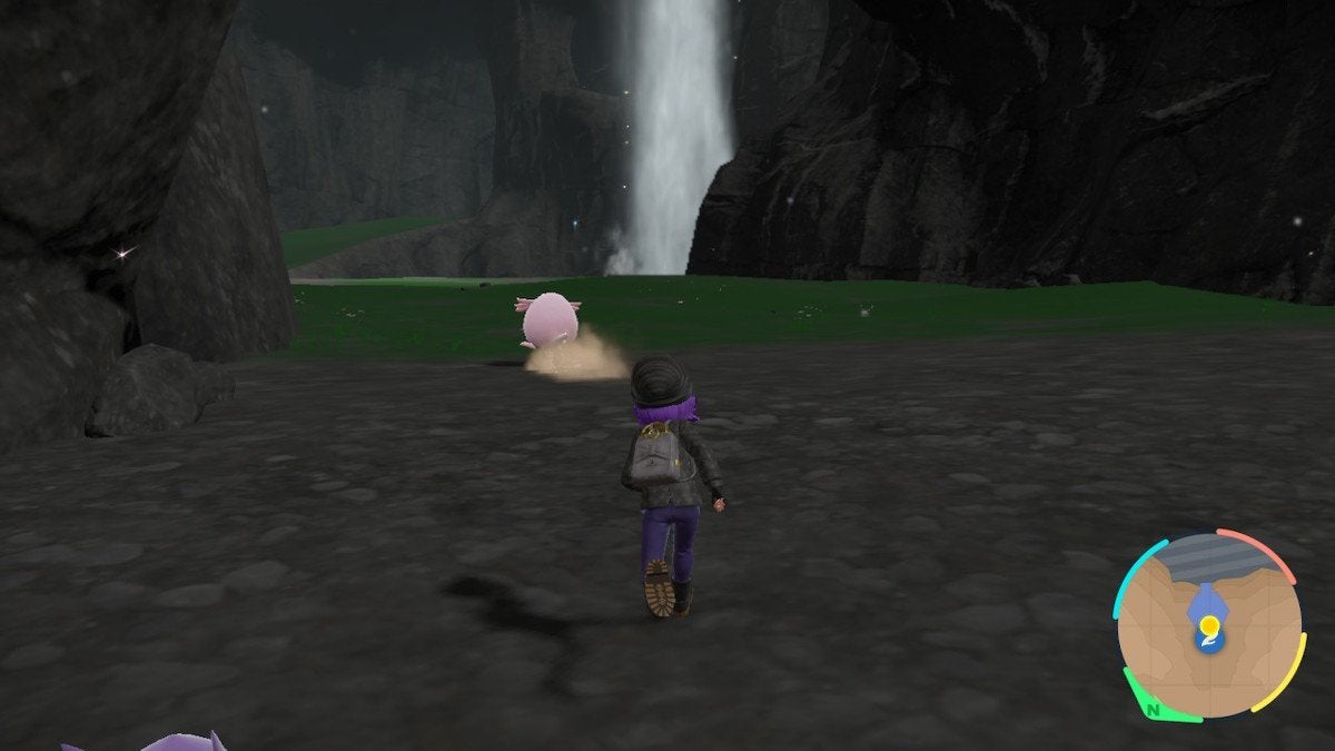 A player chasing a Chansey by a waterfall within a cave.