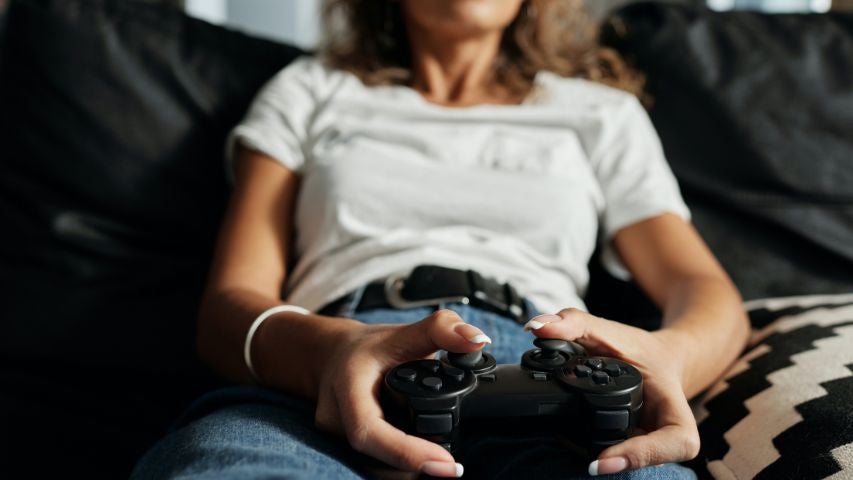 A woman playing a video game, holding a black PS4 controller