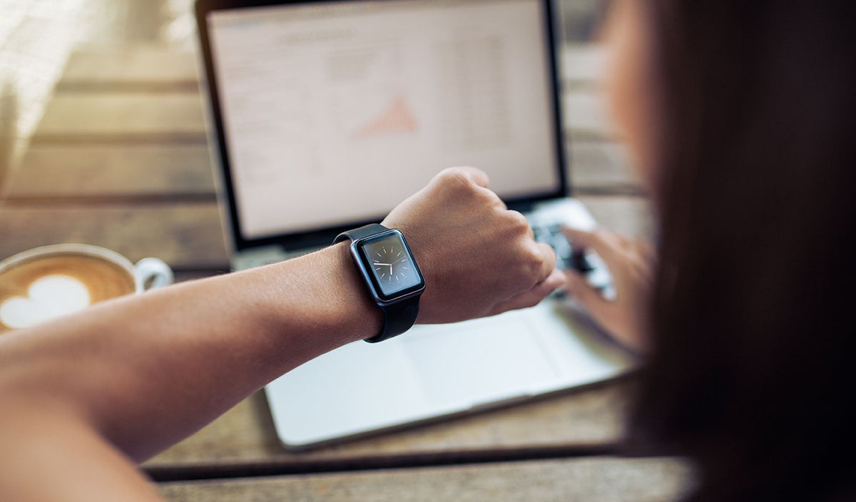 Someone checking their watch while using their laptop.