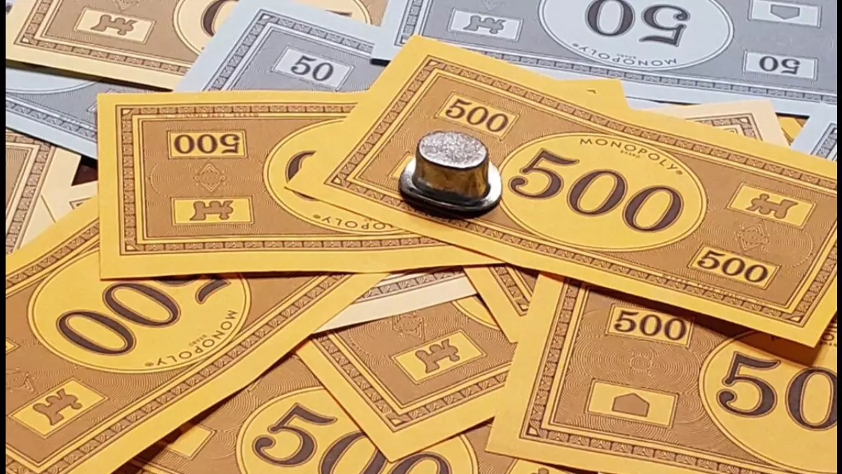 The hat piece from Monopoly sitting on top of a stack of Monopoly money.