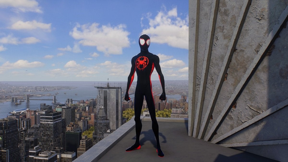 Miles Morales wearing the Across the Spider-Verse suit, which is black and red with a large circular red spider on the chest. This suit has a cartoony design and slims Miles' figure.