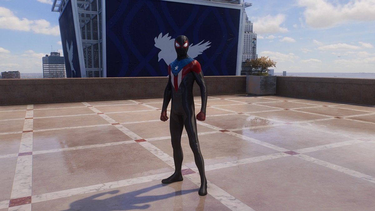 Miles Morales wearing the Boricua Suit, which is mostly black but has red, white, and blue on the chest. There's a white star in the blue triangle around the suit's neckline.