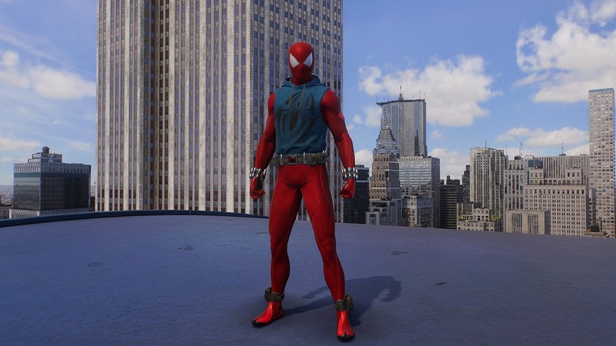 Peter Parker wearing the Scarlet Spider Suit, which is all red with a blue tank top over the chest area. There's a large black spider on the tank top. This suit comes with studded wrist bands and a black belt.
