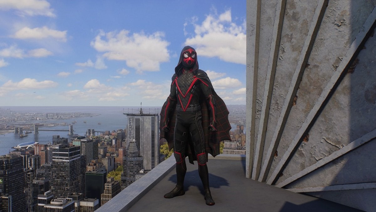 Miles Morales wearing the Shadow Spider Suit, which is mostly black with red trim. It comes with a hood and a jagged cape.