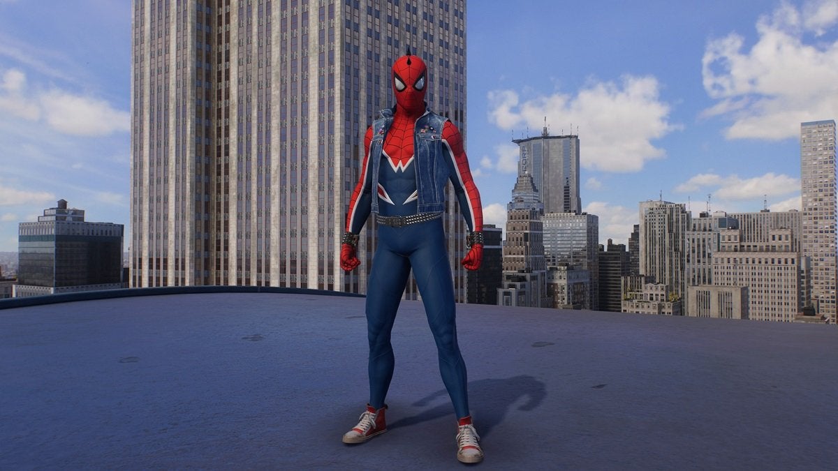 Peter Parker wearing the Spider-Punk suit, which is blue and red. It comes with a blue vest, studded wristbands, and a studded belt. The head of the suit also has a black spike mohawk.