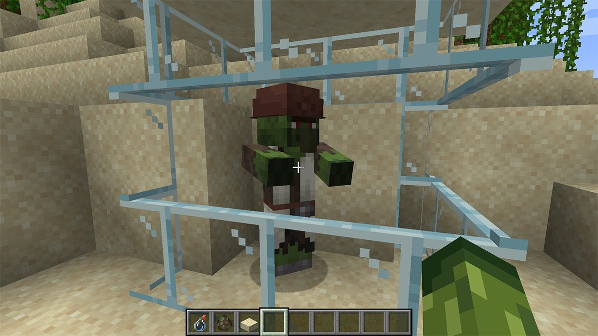 A Villager Zombie in Minecraft trapped within a glass and sand prison.